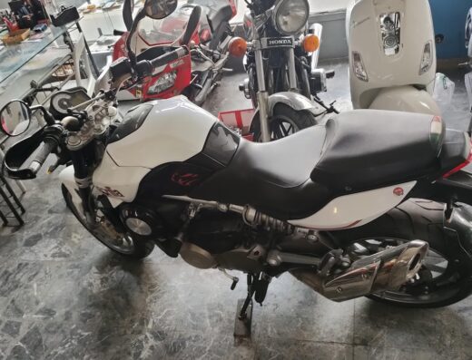 Esposizione di moto usate e scooter in vendita da Euromoto, inclusa una Benelli bianca, una Honda e uno scooter bianco. Servizi di compravendita moto.