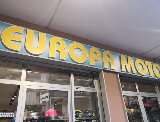 Insegna di Europa Moto S.r.l., negozio di accessori e abbigliamento per motociclisti, con vetrine che espongono caschi.