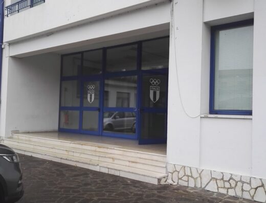 Ingresso della sede della F.M.I. (Federazione Motociclistica Italiana) con vetrate blu e logo dell'Italia, un punto di riferimento per gli appassionati di motociclismo e delle competizioni motociclistiche.