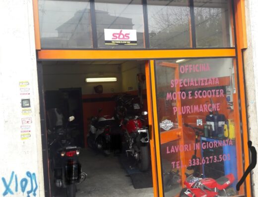 Fabio Moto Roma: Officina specializzata moto e scooter plurimarche, lavori in giornata. Vista dell'officina con moto in riparazione e mini moto Ducati esposta in vetrina.
