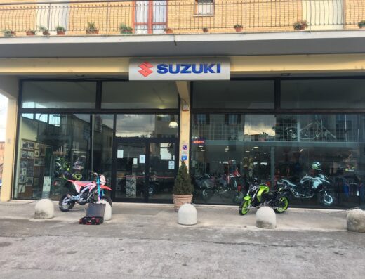 Showroom di Fantamoto con moto Suzuki esposte, accessori e caschi visibili in vetrina. Servizi di vendita e assistenza per motociclisti.