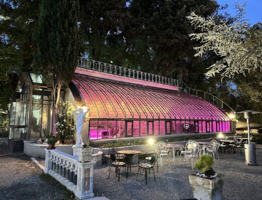 Foto del Fantastic Garden Hotel & Ristorante, Italia, che mostra una serra illuminata di rosa con tavoli da pranzo all'aperto.