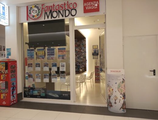 Foto dell'agenzia viaggi Fantastico Mondo con vetrina che espone offerte per Toppe Canne, Montesilvano e crociere MSC, accanto a una cabina telefonica rossa.