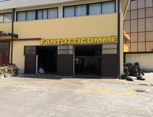 Fantozzi Gomme S.N.C.: Facciata dell'officina con insegna "Fantozzi Gomme", ingresso aperto e pneumatici impilati. Servizi per moto e auto.