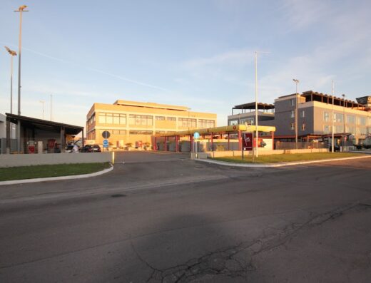 Immagine di un autolavaggio fast wash con diverse postazioni coperte e un edificio moderno sullo sfondo, ideale per la pulizia rapida della tua moto.