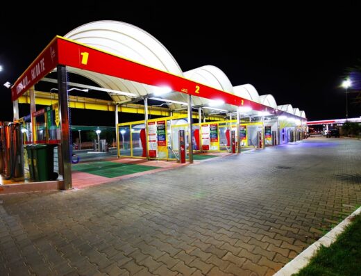 Autolavaggio self-service illuminato di notte, con postazioni multiple per la pulizia di moto e altri veicoli, ideale per motociclisti in viaggio.