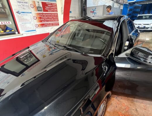 Auto nera di lusso in un autolavaggio FastWash con la portiera aperta, pronta per il servizio di pulizia e manutenzione veicoli