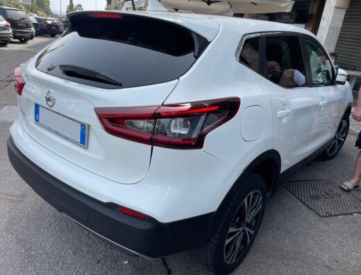 Noleggio auto senza carta di credito Fata Morgana Rent: dettaglio del retro di una Nissan Qashqai bianca parcheggiata in strada.