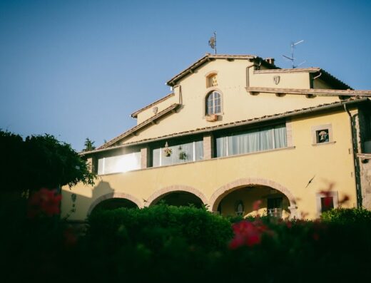 Fattoria degli Usignoli: vista esterna dell'edificio principale con archi in pietra, finestre e vegetazione circostante.