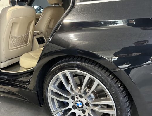 Dettaglio di un'auto nera, con portiera aperta che rivela interni beige e cerchi in lega argentati. Servizio di car detailing FCA.