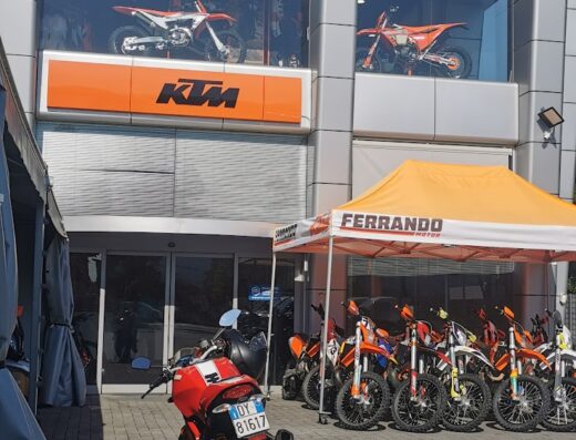 Ferrando Motor Lucca: esposizione di moto KTM, Husqvarna e Gas Gas. In primo piano, una moto rossa parcheggiata di fronte allo showroom.