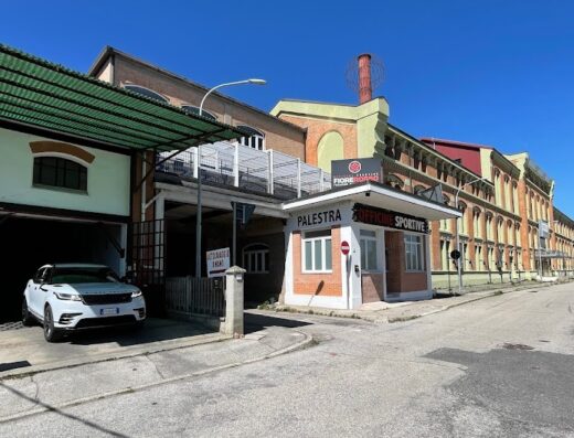 Autolavaggio a mano Ferrara: un SUV bianco Range Rover Velar parcheggiato all'interno della struttura, con insegna 'Palestra' e 'Officine Sportive' visibile.