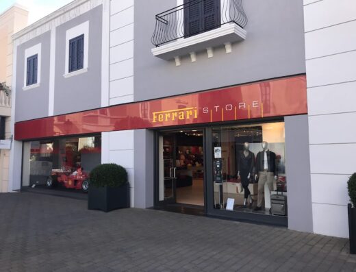 Ferrari Store ad Agira con auto da corsa in esposizione, manichini che mostrano abbigliamento e accessori di lusso in vetrina