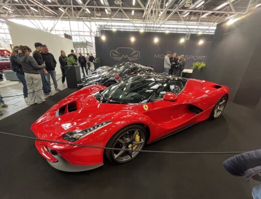 Fiera Auto e Moto d'Epoca: Una Ferrari rossa in mostra, con visitatori sullo sfondo, all'evento fieristico per auto e moto d'epoca.