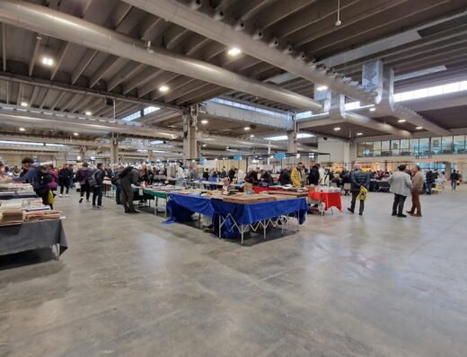 Fiera di Verona: Interno della fiera con stand espositivi e visitatori all'ingresso Porta C. Mercato di accessori e servizi per moto e viaggi.