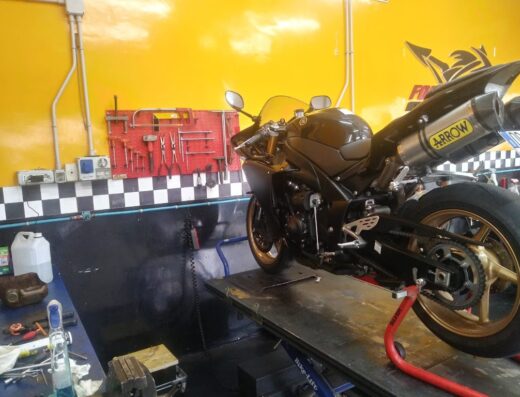 Moto Yamaha sportiva su piattaforma elevatrice presso Forcellese Moto Roma, con scarico Arrow e attrezzi sul muro. Servizi di riparazione e manutenzione moto.