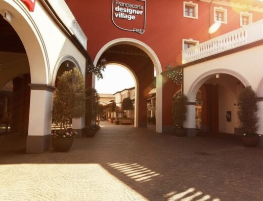 Franciacorta Designer Village: architettura esterna del centro commerciale con negozi di abbigliamento e accessori.