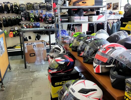 Interno di negozio Freeontime con esposizione di caschi GIVI e Scorpion, guanti da moto Dainese e stivali Alpinestars su scaffali, accessori e ricambi per motociclisti.