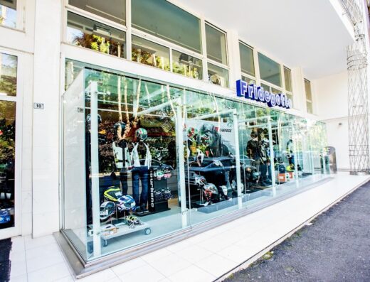 Vetrine del negozio Fridegotto S.N.C. con esposizione di abbigliamento e accessori moto: caschi, giubbotti, tute e stivali per motociclisti.