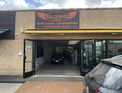 Full Service Arezzo storefront. Offers car wrapping, dark window tinting and auto accessories. Cars parked inside the service area.