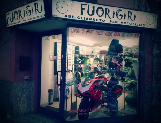 Vetrina del negozio Fuorigiri, abbigliamento per motociclisti, con esposizione di caschi moto Shark e moto Ducati rossa. Negozio di accessori e servizi per motociclisti.