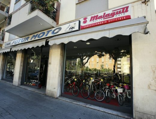 La vetrina del negozio Futur Moto di Massimiliano Martis, concessionario ufficiale Malaguti Moto, con esposizione di biciclette e moto accessori.