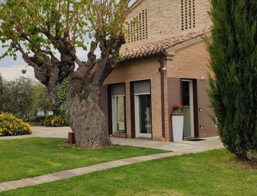 Casa di campagna Futura con prato verde curato, albero secolare e architettura tradizionale in mattoni, ideale per un soggiorno rilassante e immerso nella natura.