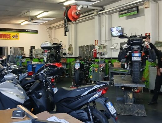 Interno di G.R. Motoservice, officina specializzata in riparazione e manutenzione moto, con diverse moto in riparazione e un meccanico al lavoro su una moto da viaggio.