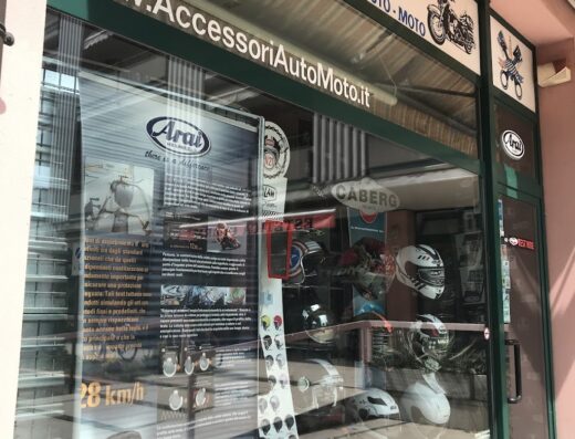 Vetrina del negozio Gama Accessori Auto Moto con esposizione di caschi Arai e Caberg. Insegna con logo e scritta "www.AccessoriAutoMoto.it".