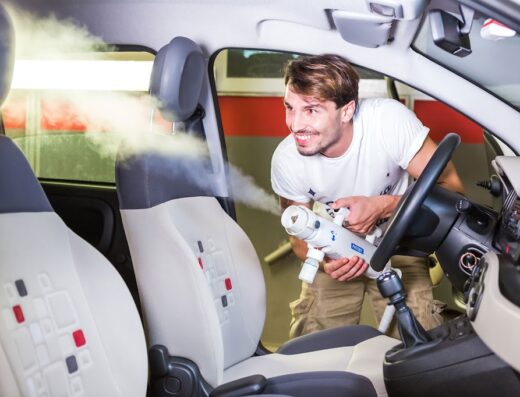 Autolavaggio Citylife Milano: Un addetto utilizza un pulitore a vapore per sanificare gli interni di un'auto, pulizia professionale e cura dei dettagli.