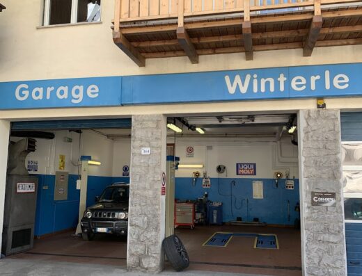 Foto del Garage Winterle, officina specializzata per moto e auto. Si vede un'auto all'interno e l'insegna del garage.