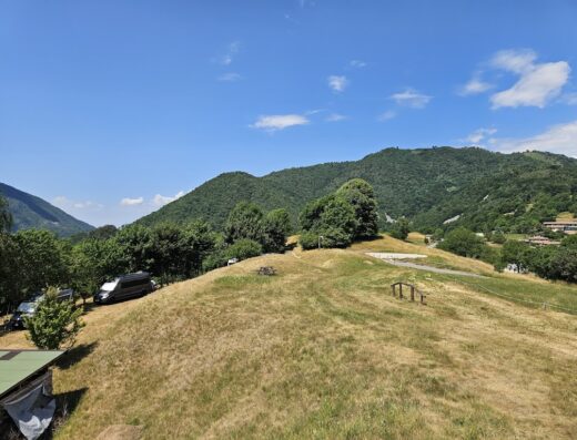 Vista panoramica di Salò, Lago di Garda, con colline verdi, prati e cielo azzurro. Ideale per il noleggio di moto e viaggi.