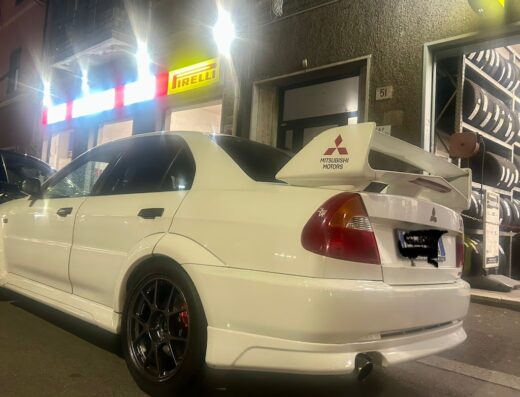 Auto sportiva Mitsubishi bianca parcheggiata di fronte a Garobbio Gomme, con pneumatici Pirelli sullo sfondo. Servizi professionali per la tua auto.