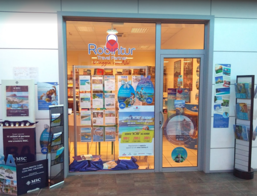 Vetrina dell'agenzia viaggi Robintur Travel Point a Cervignano, con offerte di crociere MSC e promozioni per viaggi nel Nord del Mondo.