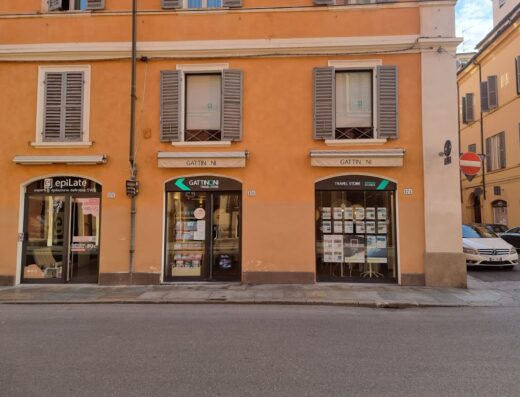 Gattinoni Travel Store a Modena, Via Emilia Centro, vetrina con offerte viaggi e pacchetti vacanza. Facciata arancione con insegna Gattinoni Travel Store.
