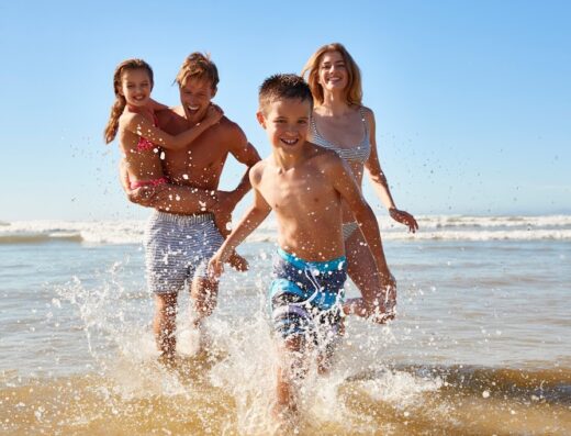 Una famiglia felice corre e gioca sulla spiaggia durante un viaggio, godendosi il sole e il mare.