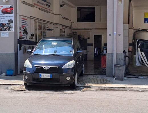 Auto nera parcheggiata di fronte all'autolavaggio Geca, in attesa del servizio di pulizia e detailing auto.