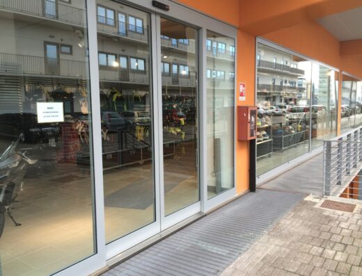 Ingresso del negozio Generazionemoto con vetrine che mostrano abbigliamento e accessori moto, parcheggio auto e moto visibili.