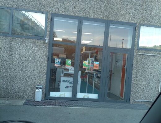 Ingresso di Genova Camper S.r.l., negozio di accessori e ricambi per moto e camper, con vetrine che mostrano prodotti in vendita.