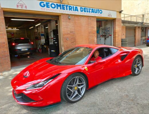 Ferrari rossa parcheggiata di fronte a Geometria dell'Auto S.r.l., officina specializzata in servizio elettronico per autovetture.
