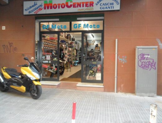 GF Motocenter store front with a yellow Yamaha scooter parked outside, offering motorcycle accessories, clothing, helmets, and gloves.
