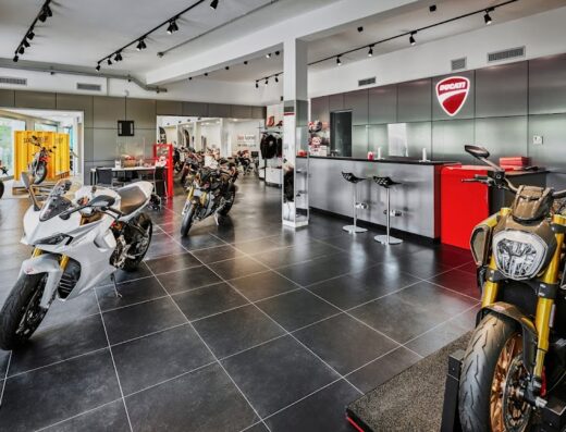 Interno di Ghezzi Moto, concessionaria Ducati con diverse moto esposte, tra cui modelli sportivi e da strada, e il logo Ducati ben visibile.