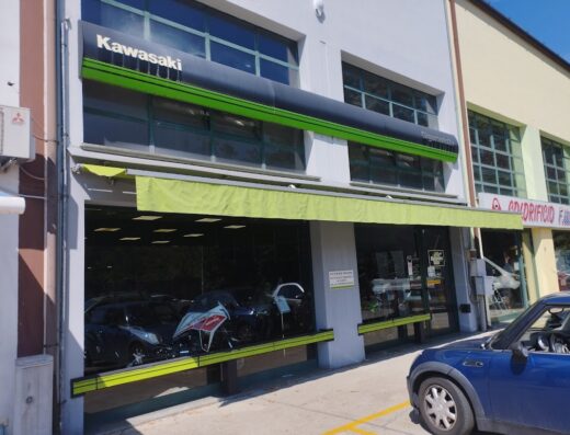 Gigamoto2+ srl: concessionaria Kawasaki con esposizione di moto e accessori. Vetrina con moto in vendita e auto parcheggiata di fronte.
