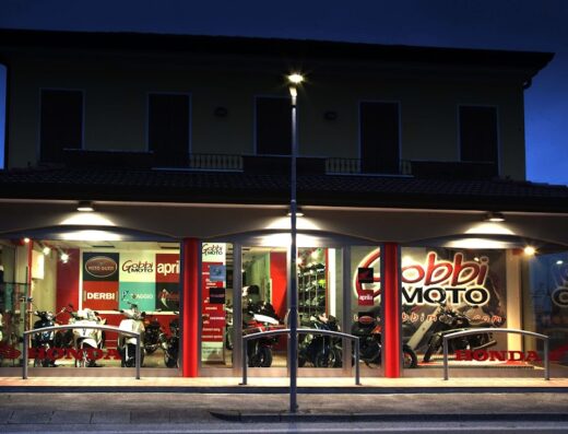 Gobbi Moto officina autorizzata MV Agusta, Moto Guzzi, Aprilia, Piaggio: Esterno dell'officina con vetrine illuminate che mostrano moto e accessori in esposizione.