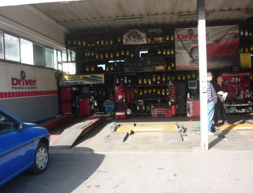Interno dell'officina Driver Center Pirelli a Terni, specializzata in pneumatici e assistenza per moto e auto, con scaffali di gomme, attrezzature per il cambio gomme e personale.