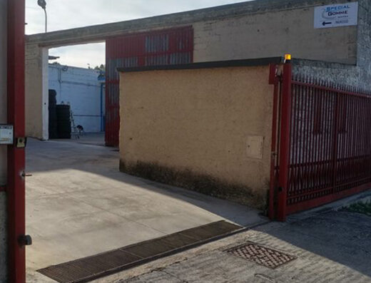 Special Gomme Matera: Esterno dell'officina con cancello rosso, ingresso e insegna indicante la direzione. Servizi di pneumatici e accessori moto.