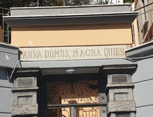 Ingresso di una villa con l'iscrizione latina "PARVA DOMUS, MAGNA QUIES" sopra la porta, dettaglio architettonico.