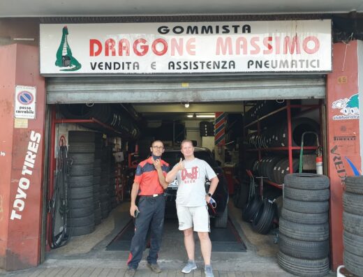 Gommista Massimo Dragone: Vendita e assistenza pneumatici. Immagine mostra l'officina con personale e cliente, scaffali di gomme e insegna del gommista.