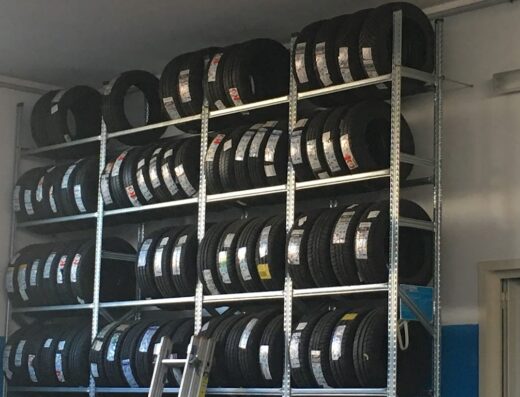 Scaffalatura metallica piena di pneumatici nuovi presso Gommista Pischedda Giulio, pronti per il montaggio e la vendita. Accessori e ricambi moto disponibili.