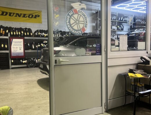 Interno dell'officina Lory Gomme a Recco, specializzata in pneumatici per auto e moto, con scaffali di gomme Dunlop e zona convergenza visibile.